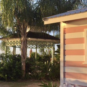 Gazebo and pretty pink chattel house on a Barbados sunset beach with palm trees