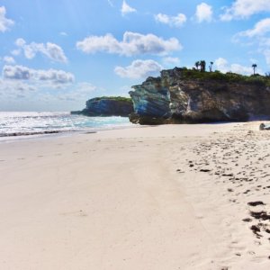 Long flat white Bahamas beach with magnificently shaped massive rocks