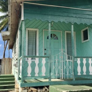 Chattelhouse from wood in turquoise color with small porch before entrance door