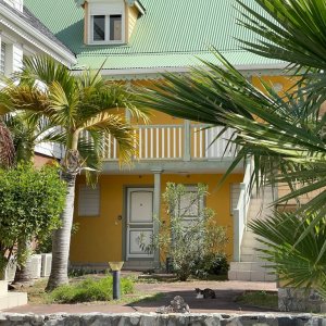 French style two floor yellow house with outside stairs and porch