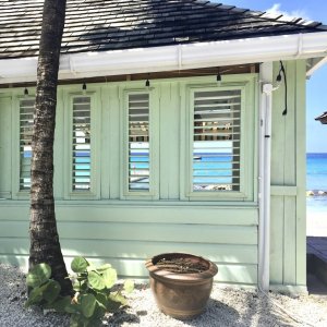 Light green wooden veranda front with open shatters to look through towards the sea