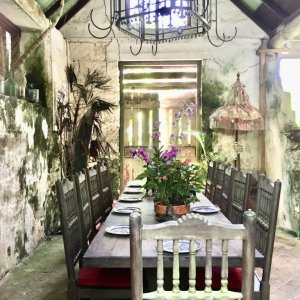 Boho decor of dining room in old mansion surrounded by beauttiful coloured flower garden