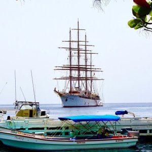 Pier construction of wood with small fishing boats water taxi and the elegant three master cruise ship sea cloud in St. Lucia