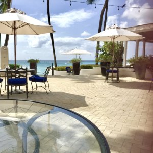 Terrace of luxury hotel with tables and white parasols overlooking beach and blue sea